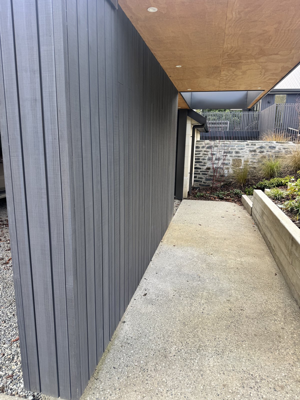 Dark modern vertical exterior cladding beside a covered entrance